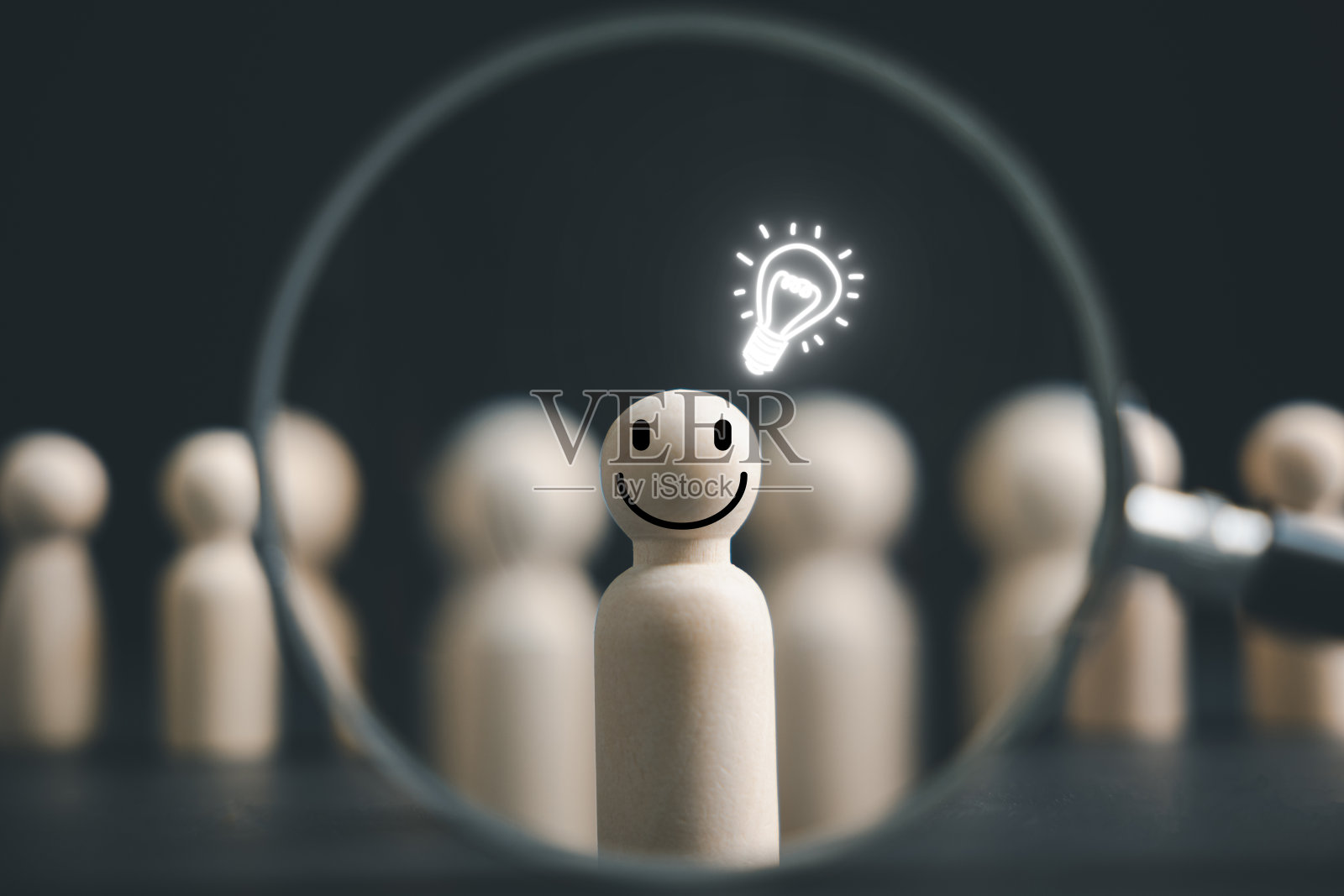 用放大镜可以看到一个快乐的木头人站在一个灯泡符号旁边照片摄影图片