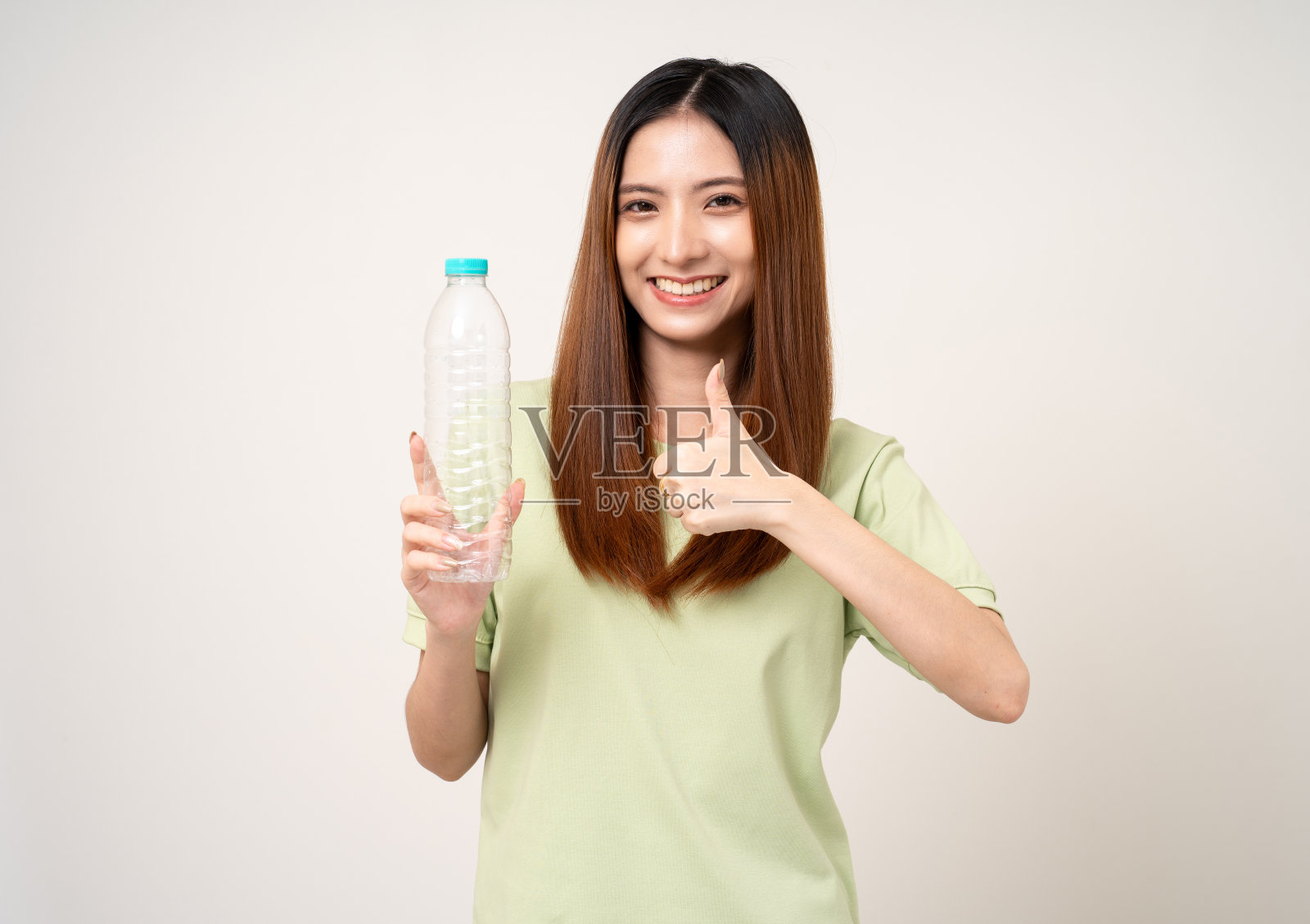 年轻的亚洲美女拿着塑料瓶进行垃圾分类，然后把它们扔进垃圾桶。积极的环保女性，穿着绿色衬衫，有着回收和可持续发展的理念。照片摄影图片