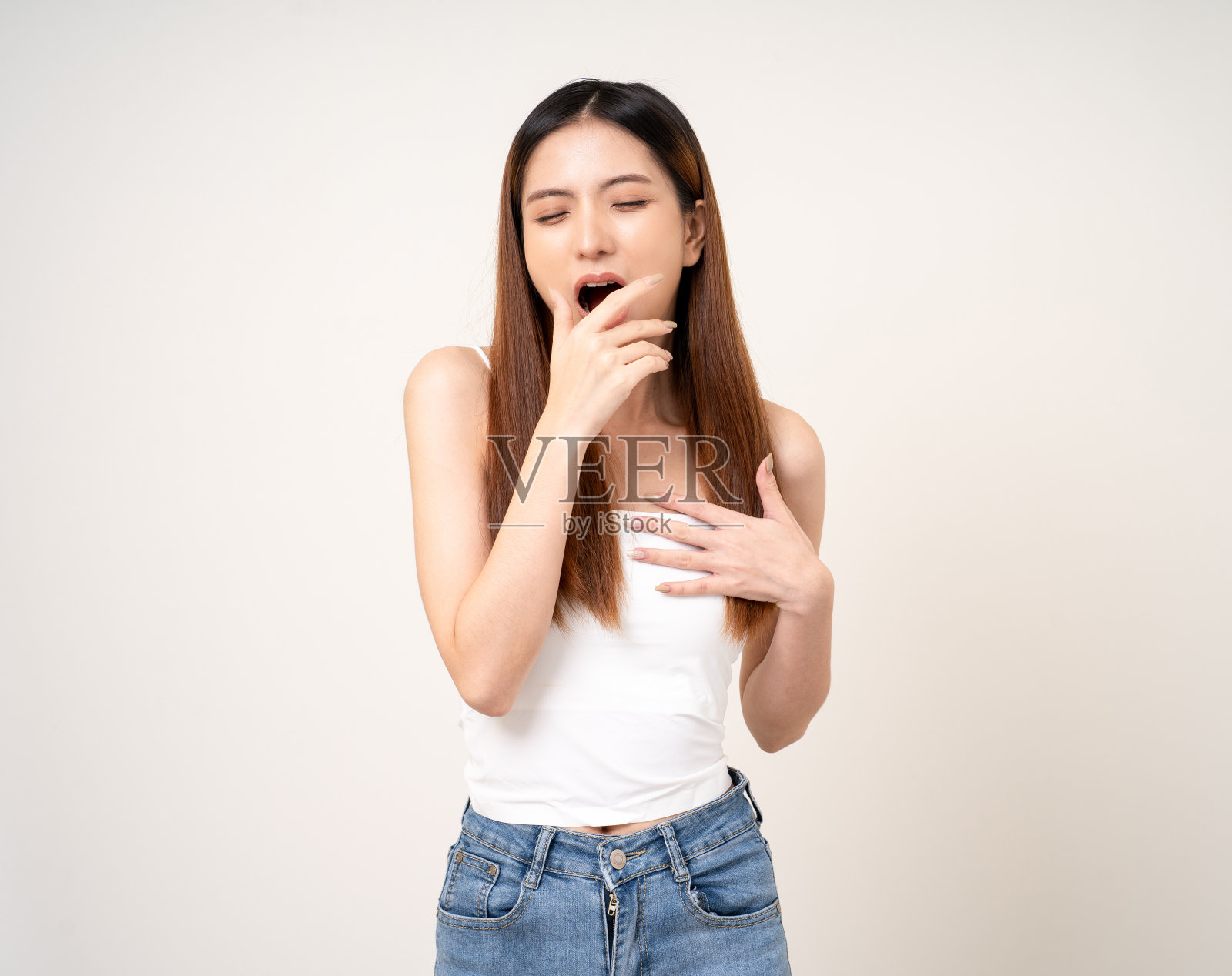 打哈欠的年轻亚洲女人她晚上不睡觉。休息不够。昏睡的雌性在孤立的白色背景上。用手捂住嘴。照片摄影图片