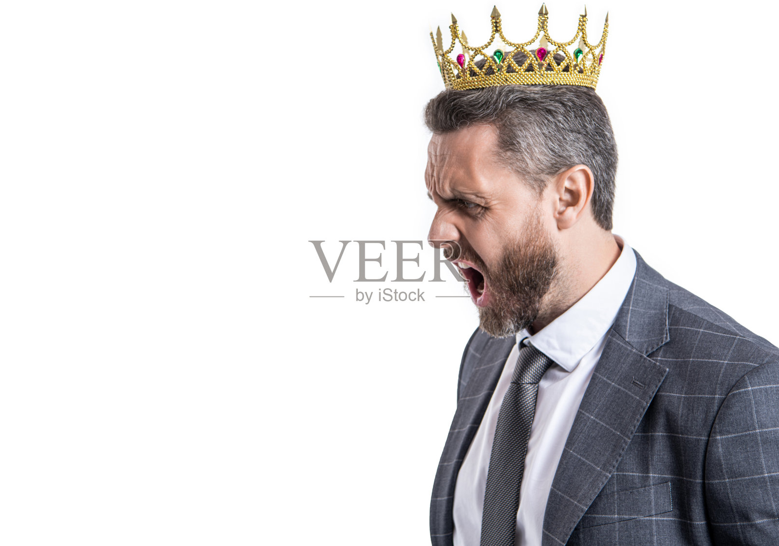 西装革履、头戴皇冠的愤怒商人在办公室里对着一个孤立在白板上的人大喊大叫照片摄影图片