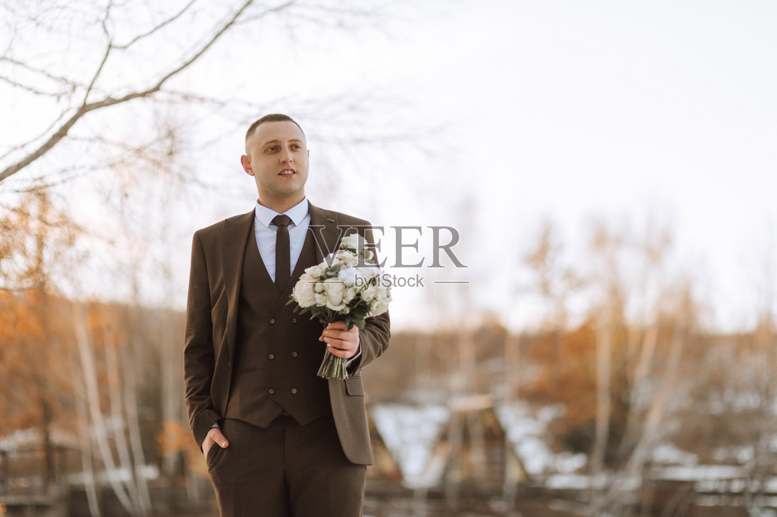 新郎手捧花束，一边走一边摆姿势。冬季婚礼。肖像照片摄影图片