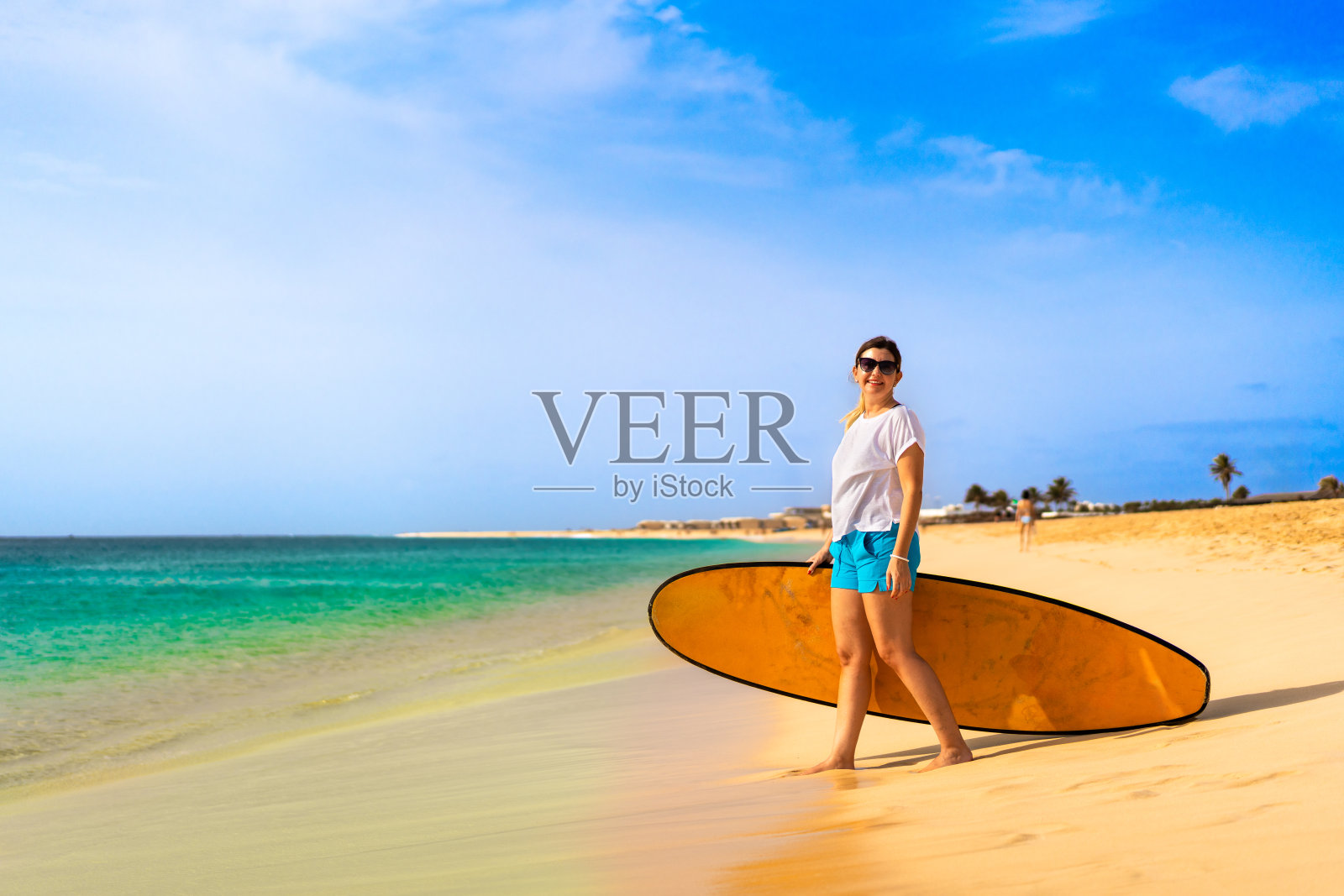 美丽的女人拿着冲浪板站在阳光明媚的海滩圣玛丽亚，萨尔岛，佛得角照片摄影图片