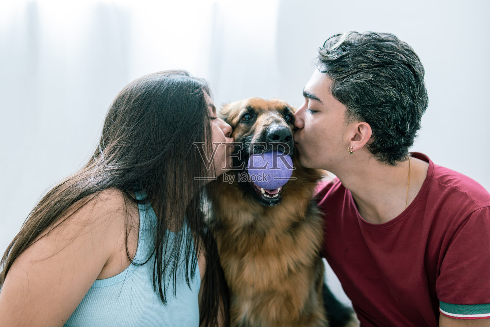 快乐的拉丁美洲夫妇亲吻德国牧羊犬照片摄影图片