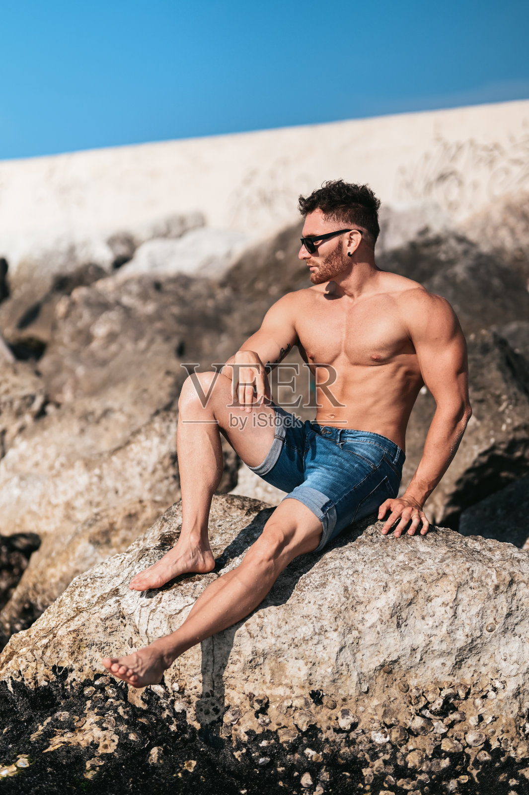 一个英俊的时尚模特在海滩岩石上的肖像。照片摄影图片