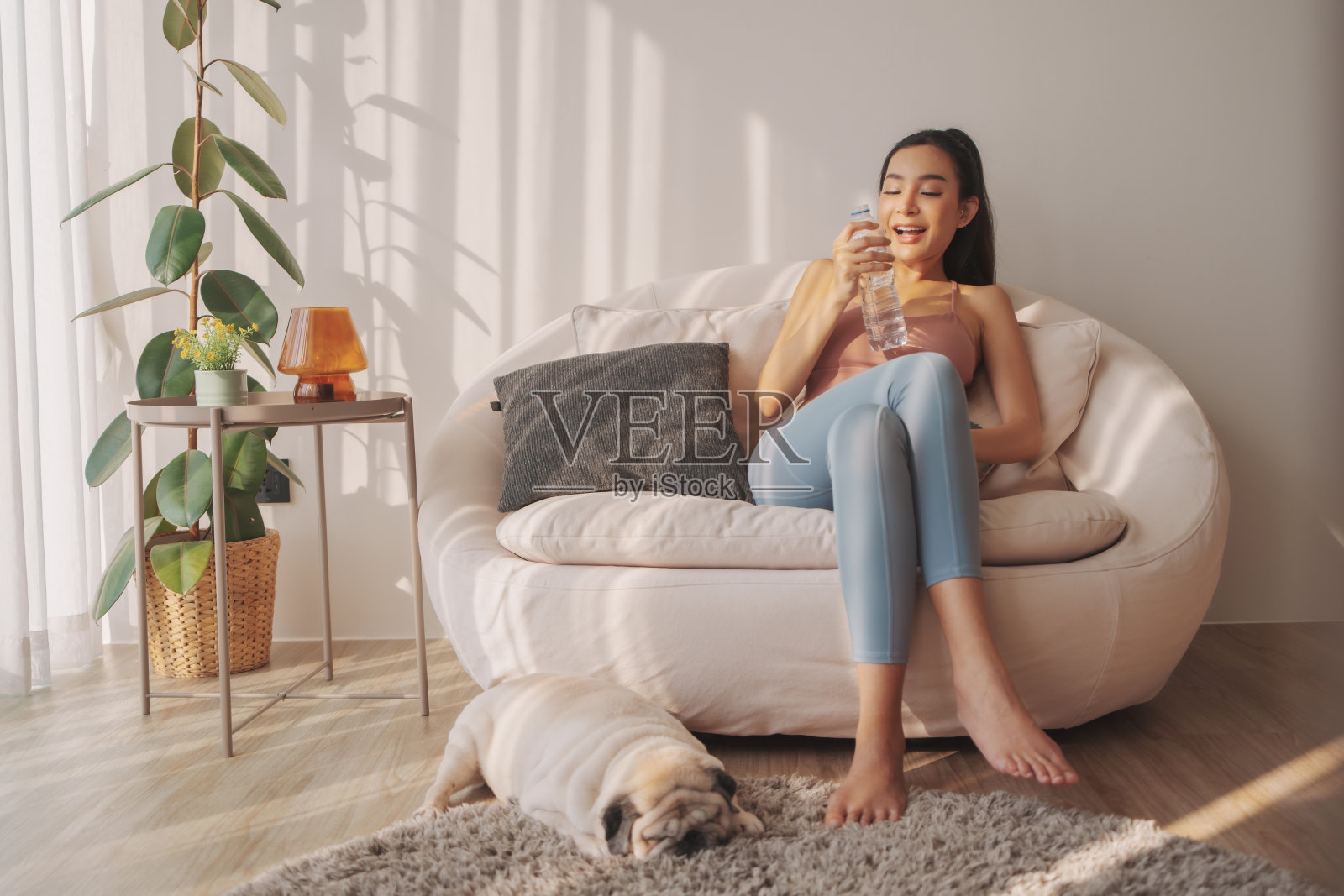 瑜伽后补水，女人拿着水瓶和哈巴狗照片摄影图片