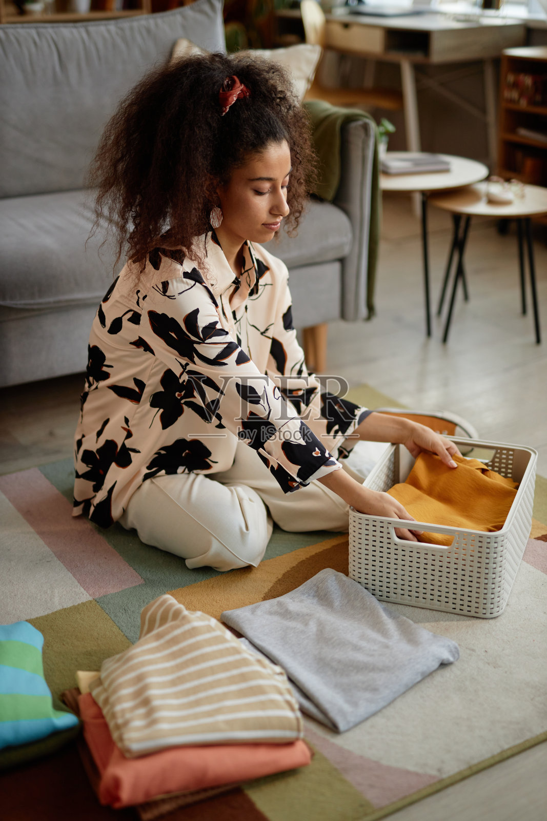 洗衣日，一名妇女在折叠和分类干净的衣服照片摄影图片