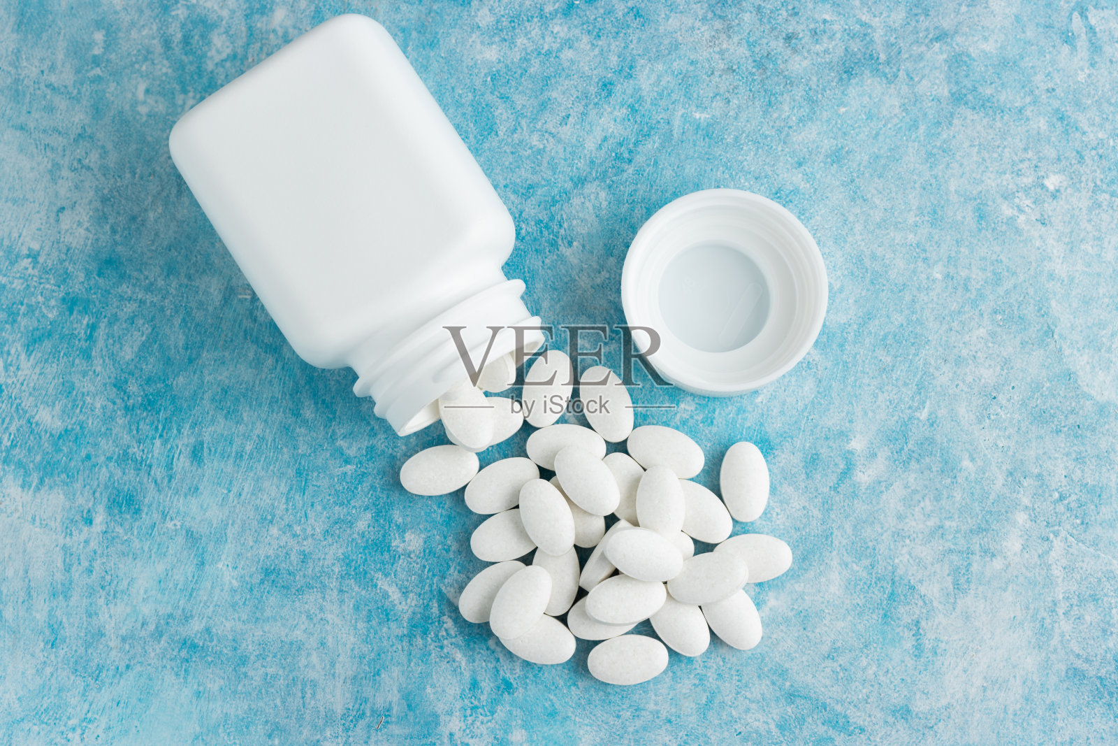 白色医疗药丸，蓝色背景的药物或治疗药片，维生素和矿物质，营养或膳食补充剂，俯视图照片摄影图片