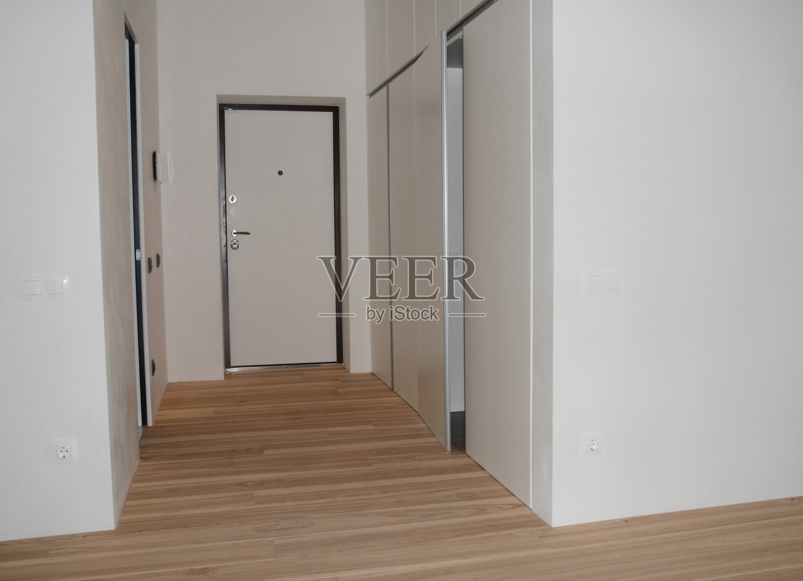 简单，极简主义的入口大厅设计，白色的墙壁，门，内置衣柜和木地板在装修后的公寓。现代公寓的入口。照片摄影图片