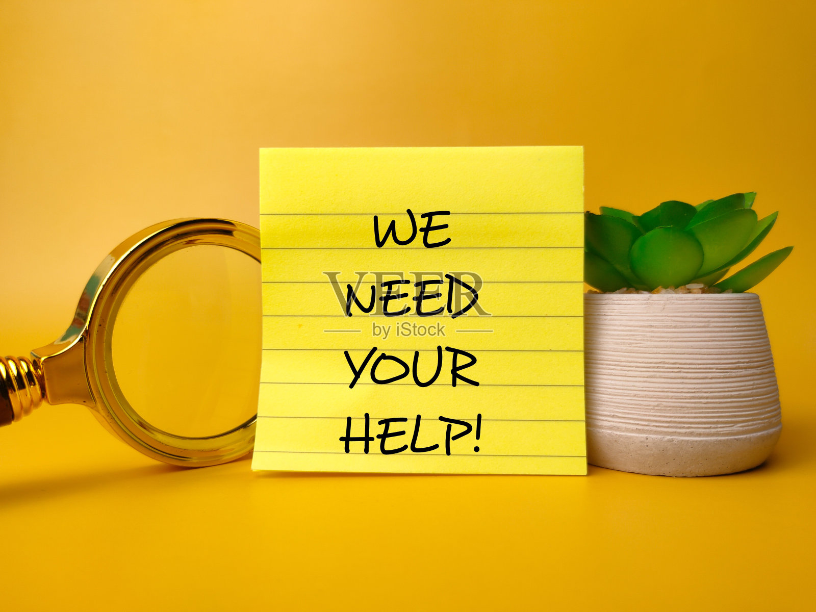 插上放大镜，写上“我们需要你的帮助”照片摄影图片