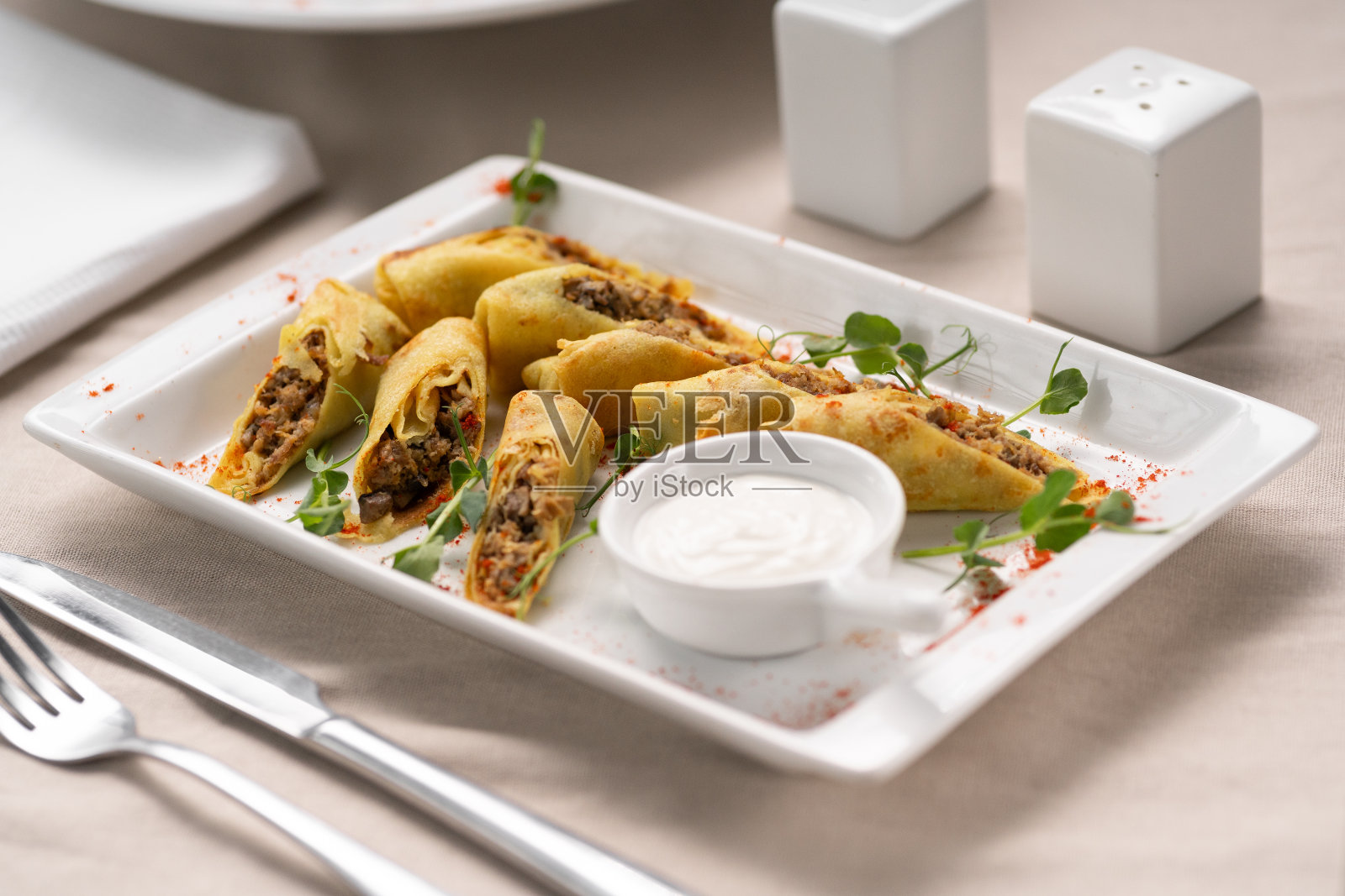白盘子里的牛肉馅可丽饼配酸奶油照片摄影图片