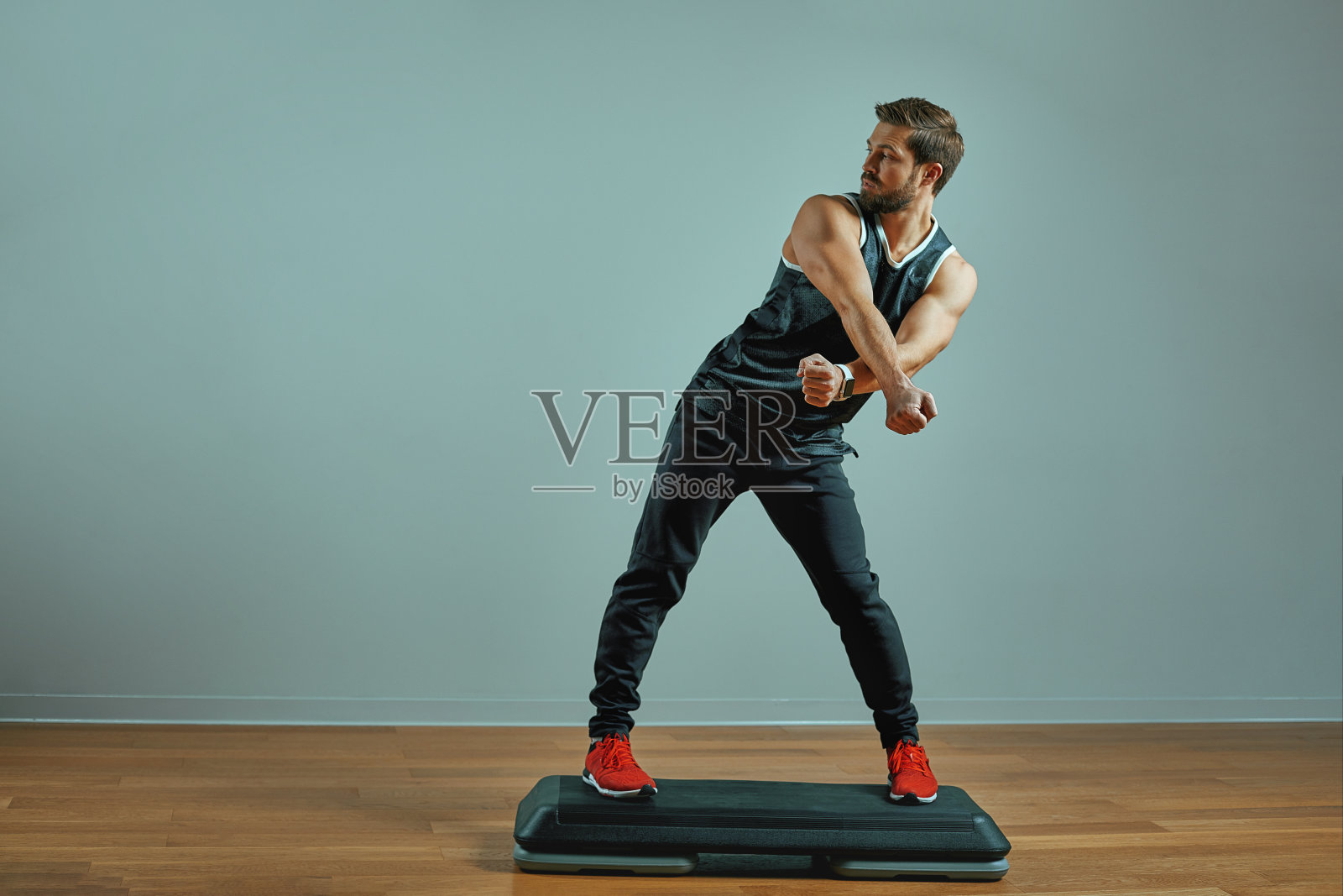 肌肉发达的年轻人在工作室灰色背景下的台阶平台上训练照片摄影图片