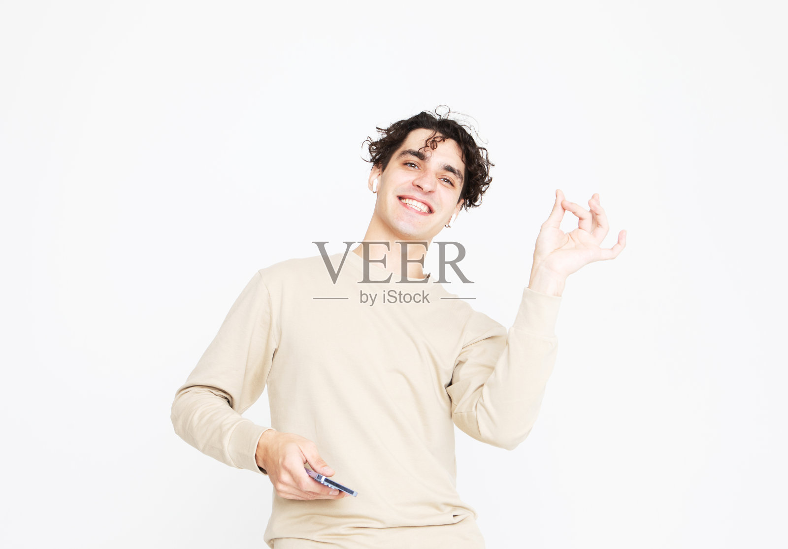 一个穿着米色毛衣的欢快的年轻人在白色的工作室背景上跳舞，享受生活照片摄影图片