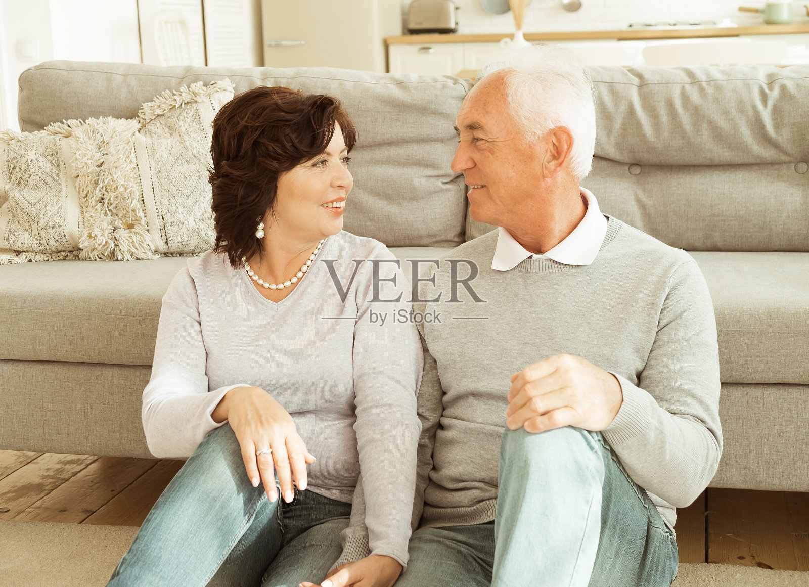 一对老夫妇坐在客厅的地板上拥抱。关系和家庭观念。照片摄影图片