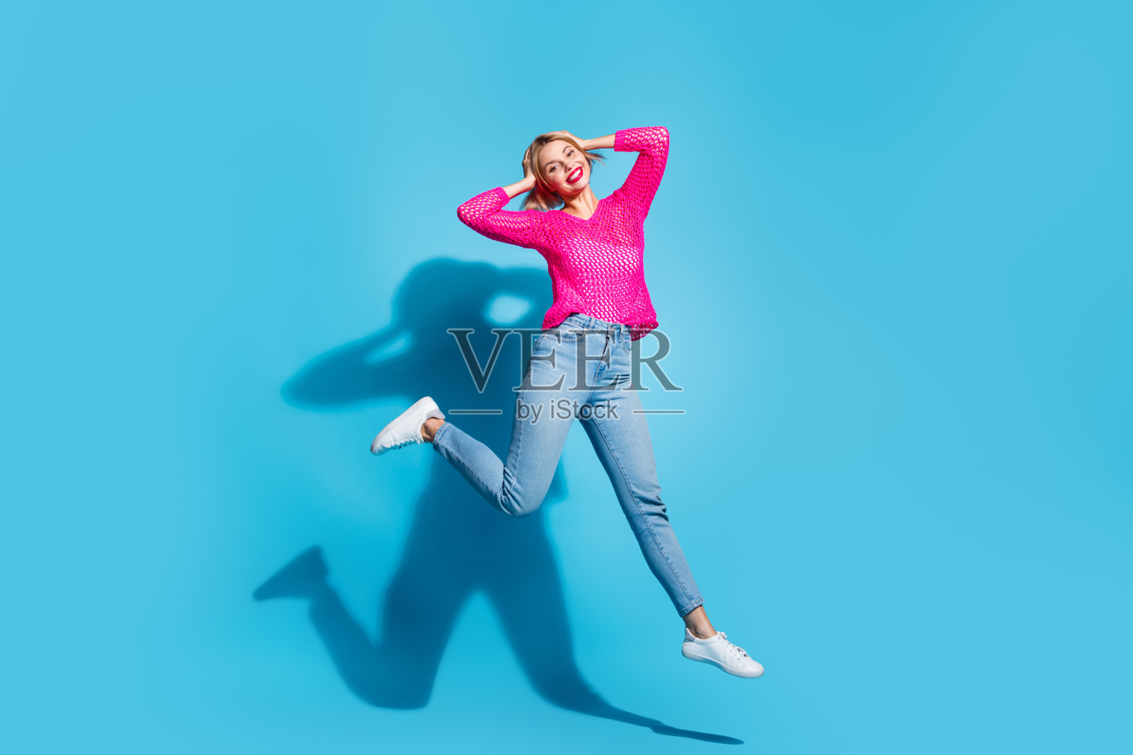 迷人的年轻女子的全身照片跳碰头活动穿着时尚的粉红色针织衣服孤立的蓝色背景照片摄影图片