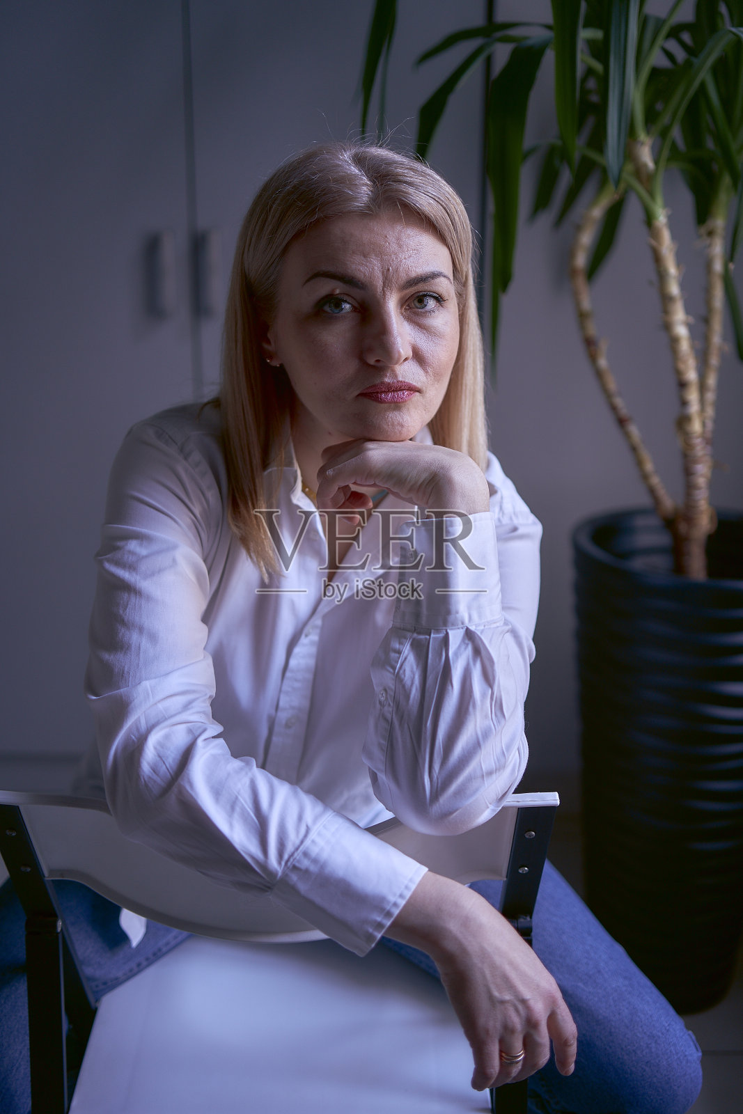 办公室里一个穿着牛仔裤和白衬衫的金发女人的画像照片摄影图片