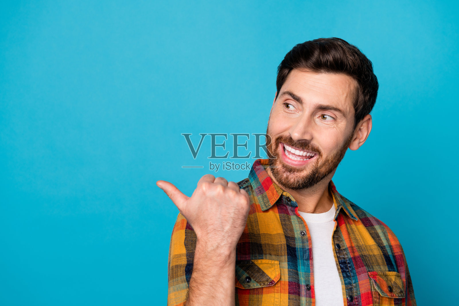 照片上乐观的男人留着胡子，穿着格子衬衫，在蓝色的背景上显示出打折的空间照片摄影图片