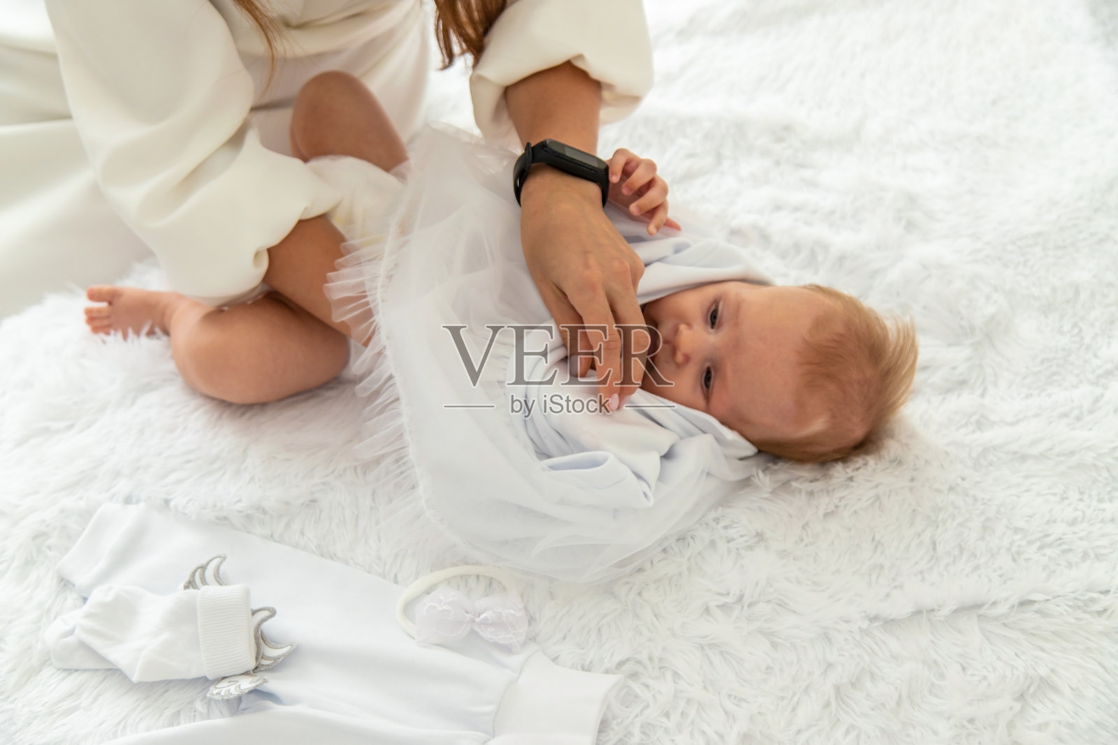 一位妇女给婴儿穿上白色的衣服照片摄影图片