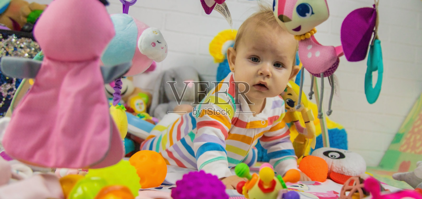 一个孩子在玩垫子上玩挂着的玩具。照片摄影图片