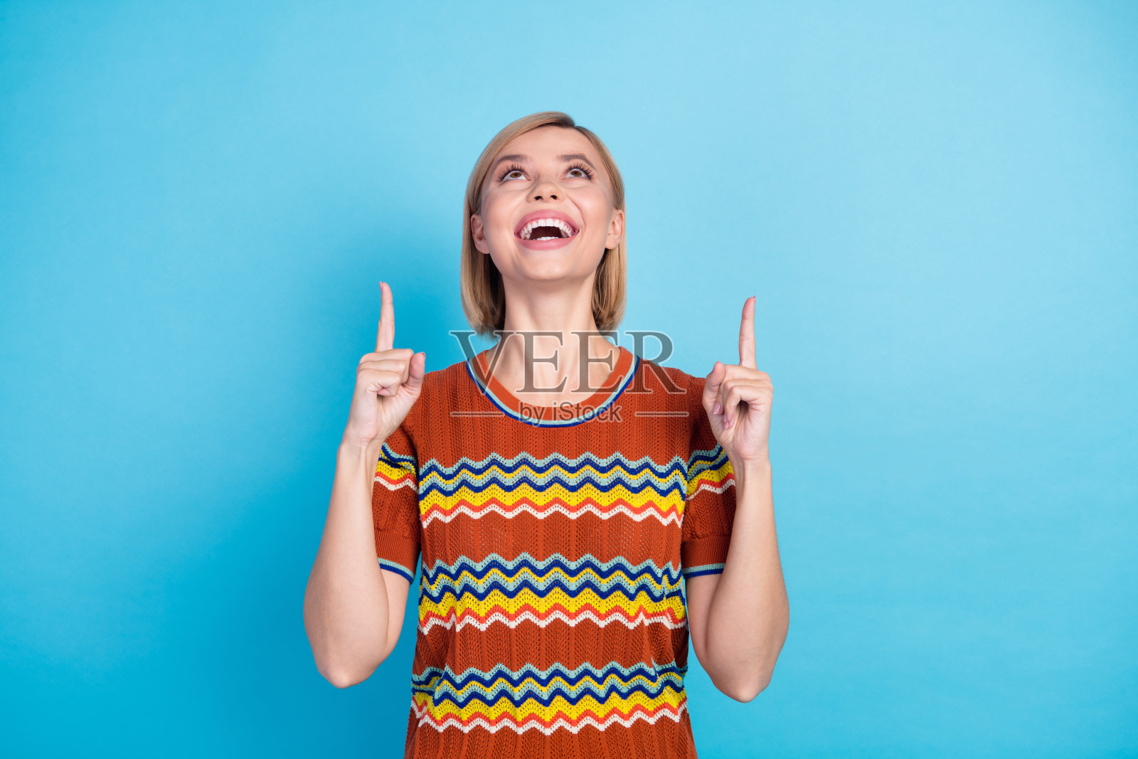 照片积极的女人与鲍勃发型穿着针织t恤看着销售空空间孤立的蓝色背景照片摄影图片