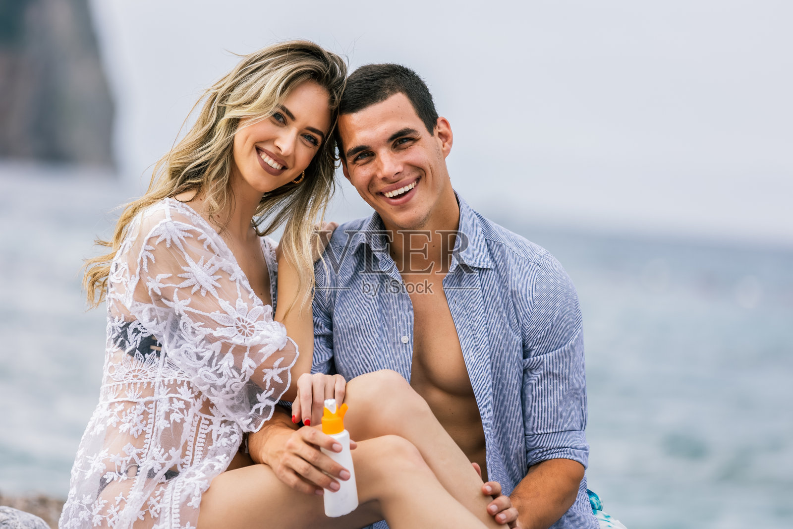 年轻夫妇在海滩上涂美黑霜照片摄影图片