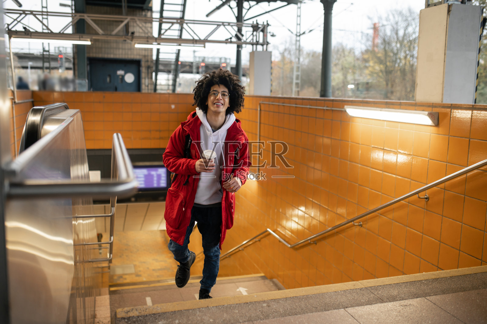 穿红夹克的旅客边喝咖啡边等火车照片摄影图片