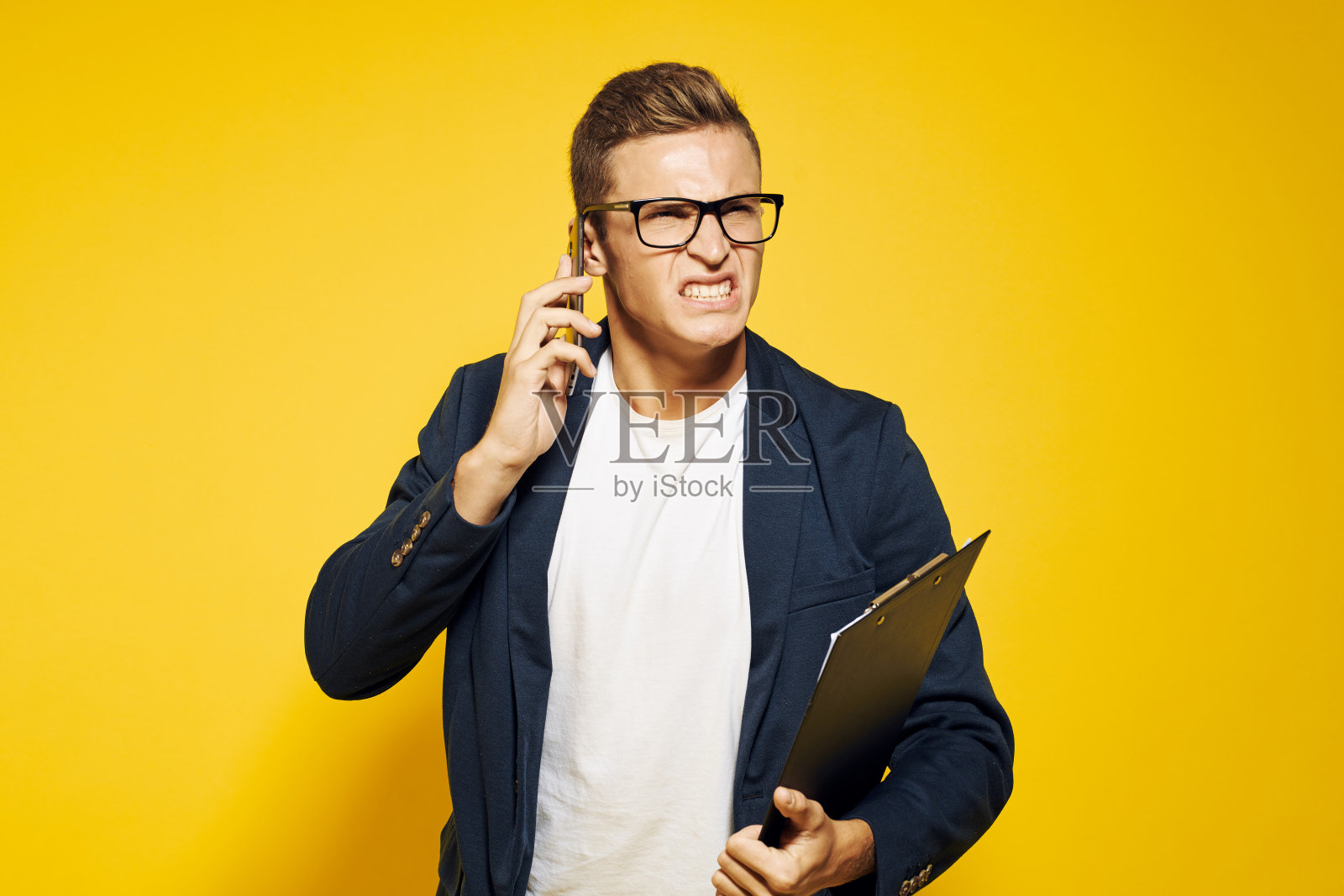 一个商人在工作，戴着眼镜，穿着黄色背景的夹克，正在打电话给员工模型照片摄影图片