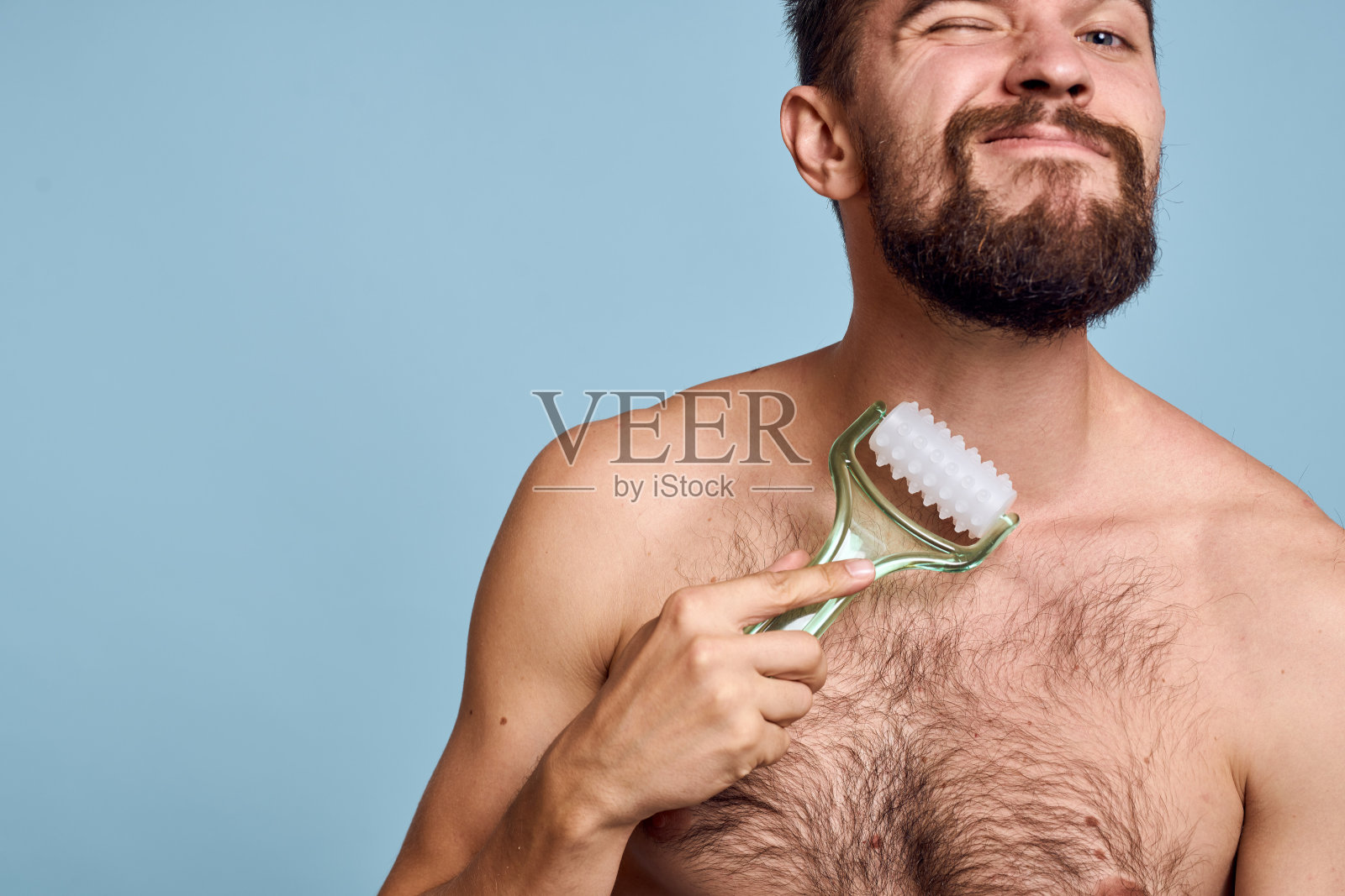 裸肩男子身体按摩器皮肤护理蓝色背景照片摄影图片