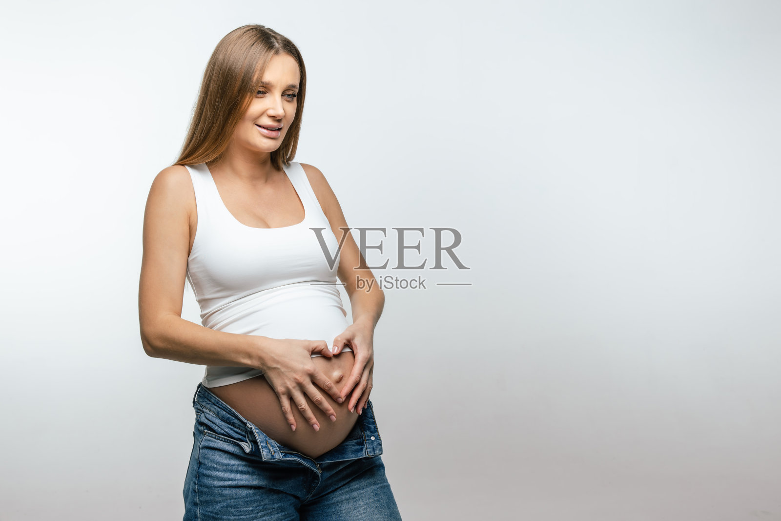 金发的年轻孕妇抱着她的大肚子照片摄影图片