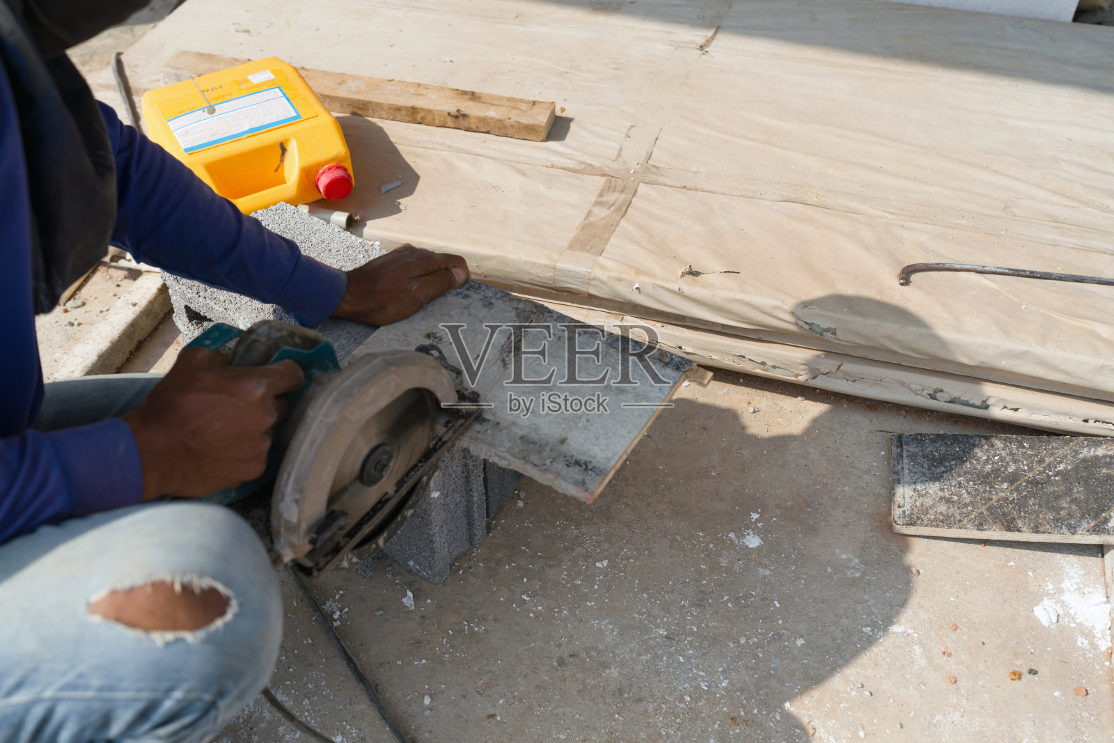 建筑工人白天在阳光下工作。用圆锯锯木头。照片摄影图片