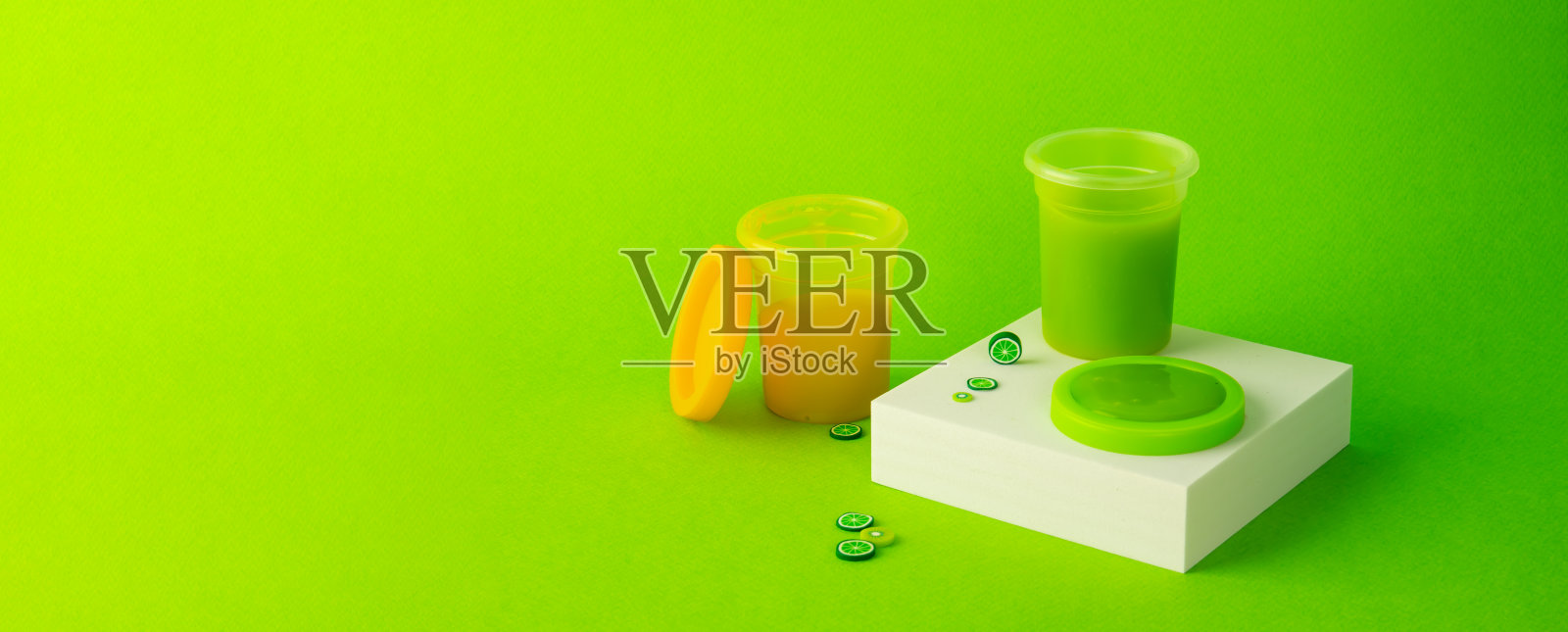 绿色的黏液从白色的立方体流到绿色的背景上。儿童游戏粘液照片摄影图片