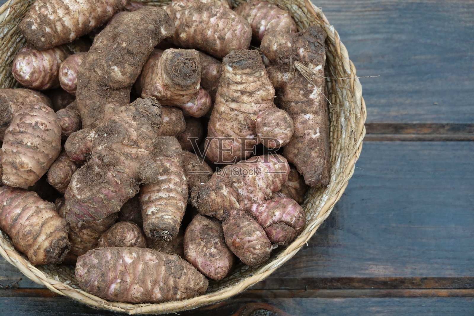 柳条篮子与耶路撒冷洋蓟收获木制背景。超级食物topinambur照片摄影图片