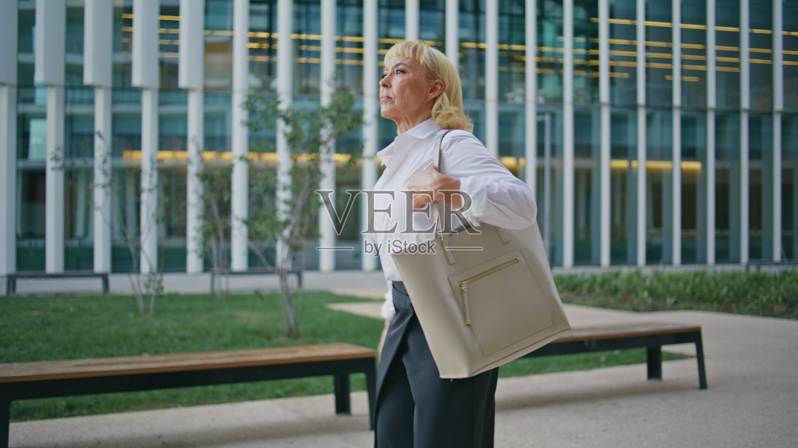 自信的退休老人走在办公楼的大街上。年老的女商人照片摄影图片