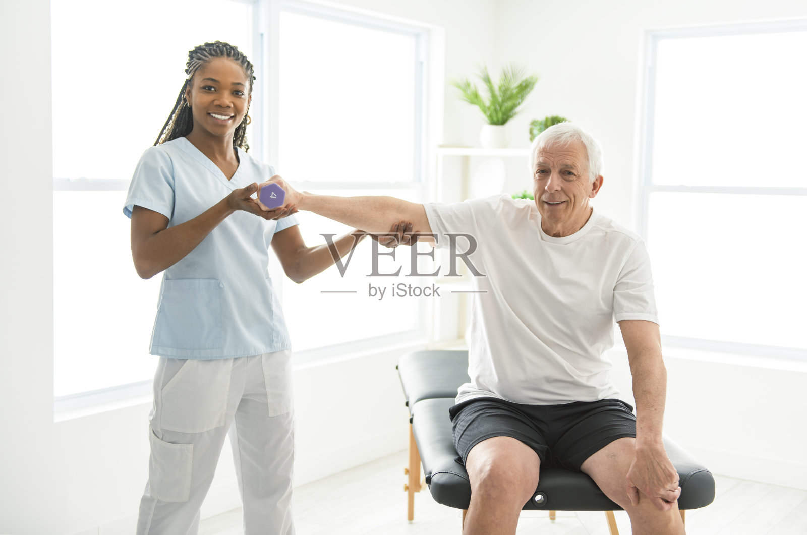 黑人理疗师在诊所帮助老人。一位老人因受伤正在接受物理治疗照片摄影图片