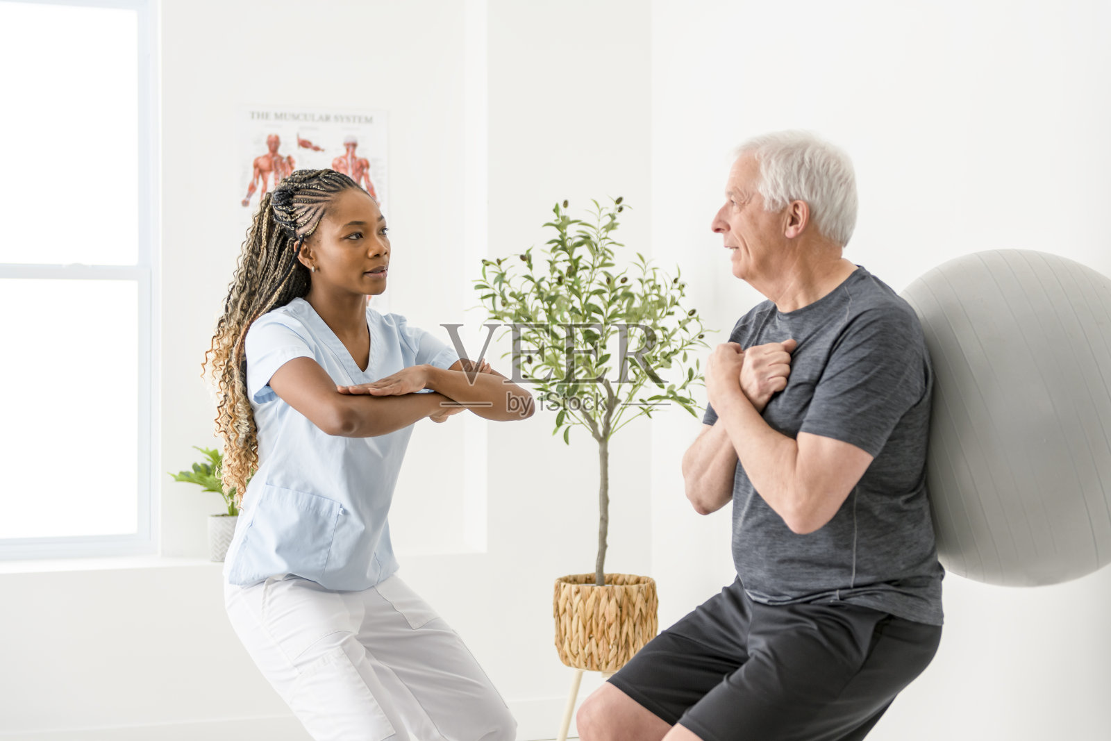 黑人理疗师在诊所帮助老人。一位老人因受伤正在接受物理治疗照片摄影图片