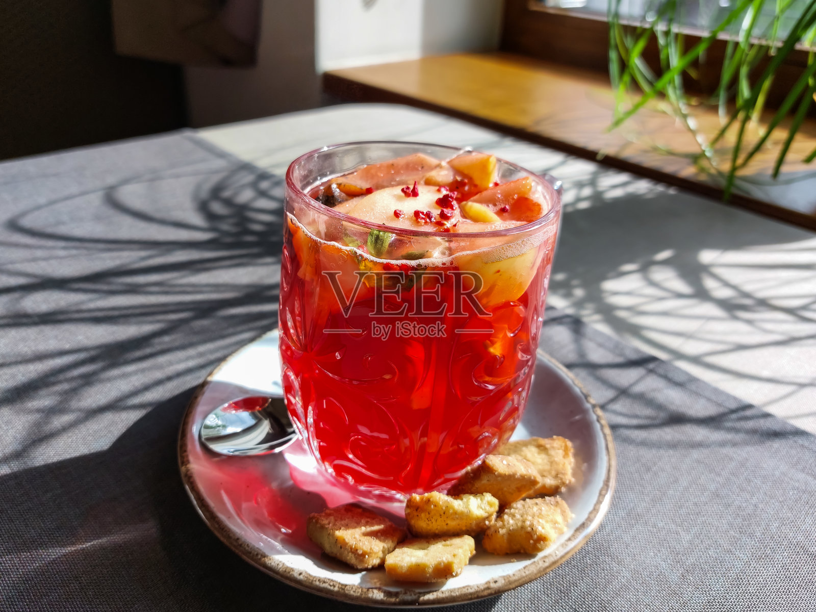 在明亮的阳光下，咖啡馆的桌子上放着一个盛着石榴和水果的热茶杯，旁边是饼干照片摄影图片