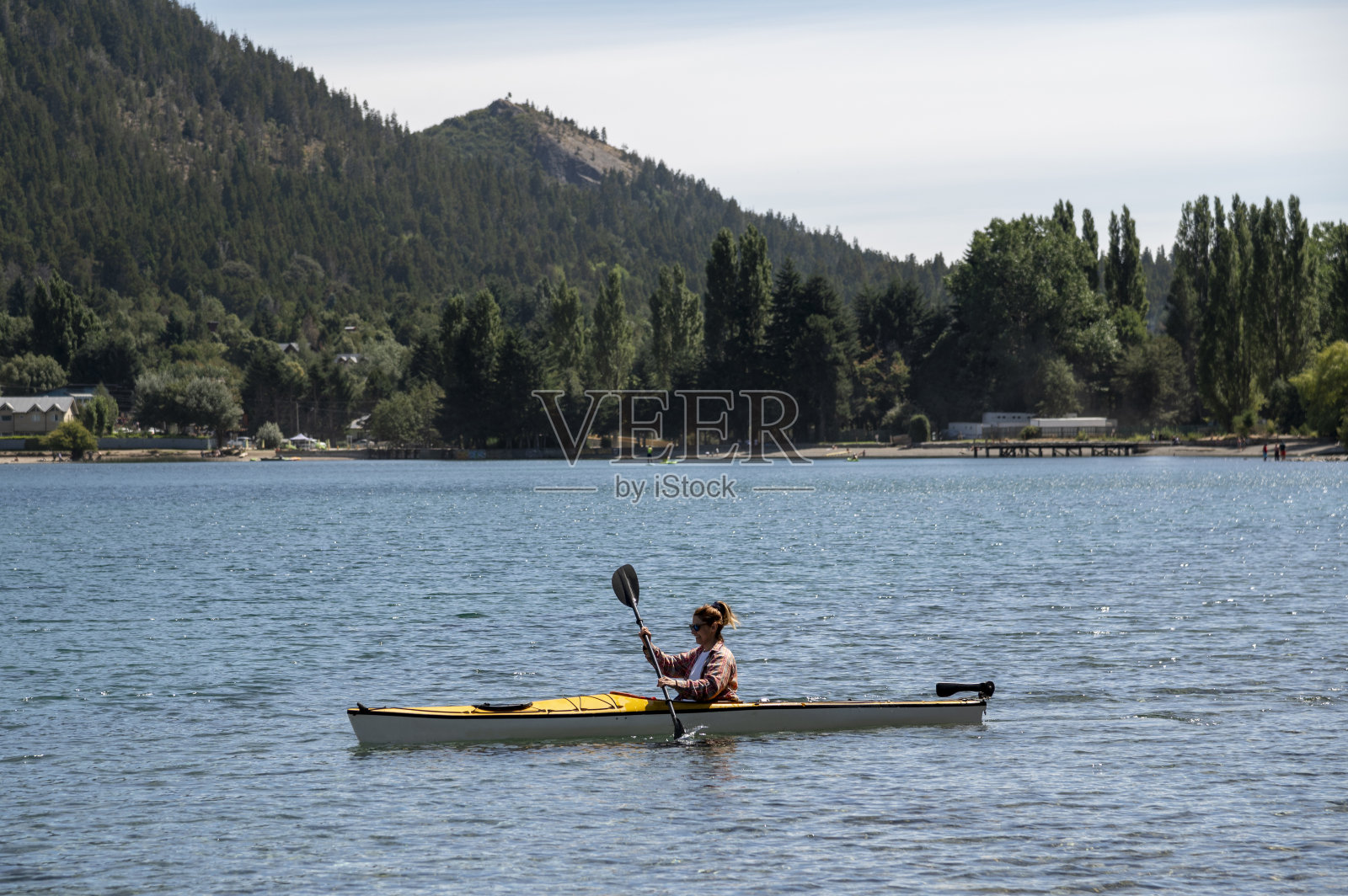 一名年轻女子在夏季游览巴里洛切湖时，划着皮艇享受着风景和阳光。照片摄影图片