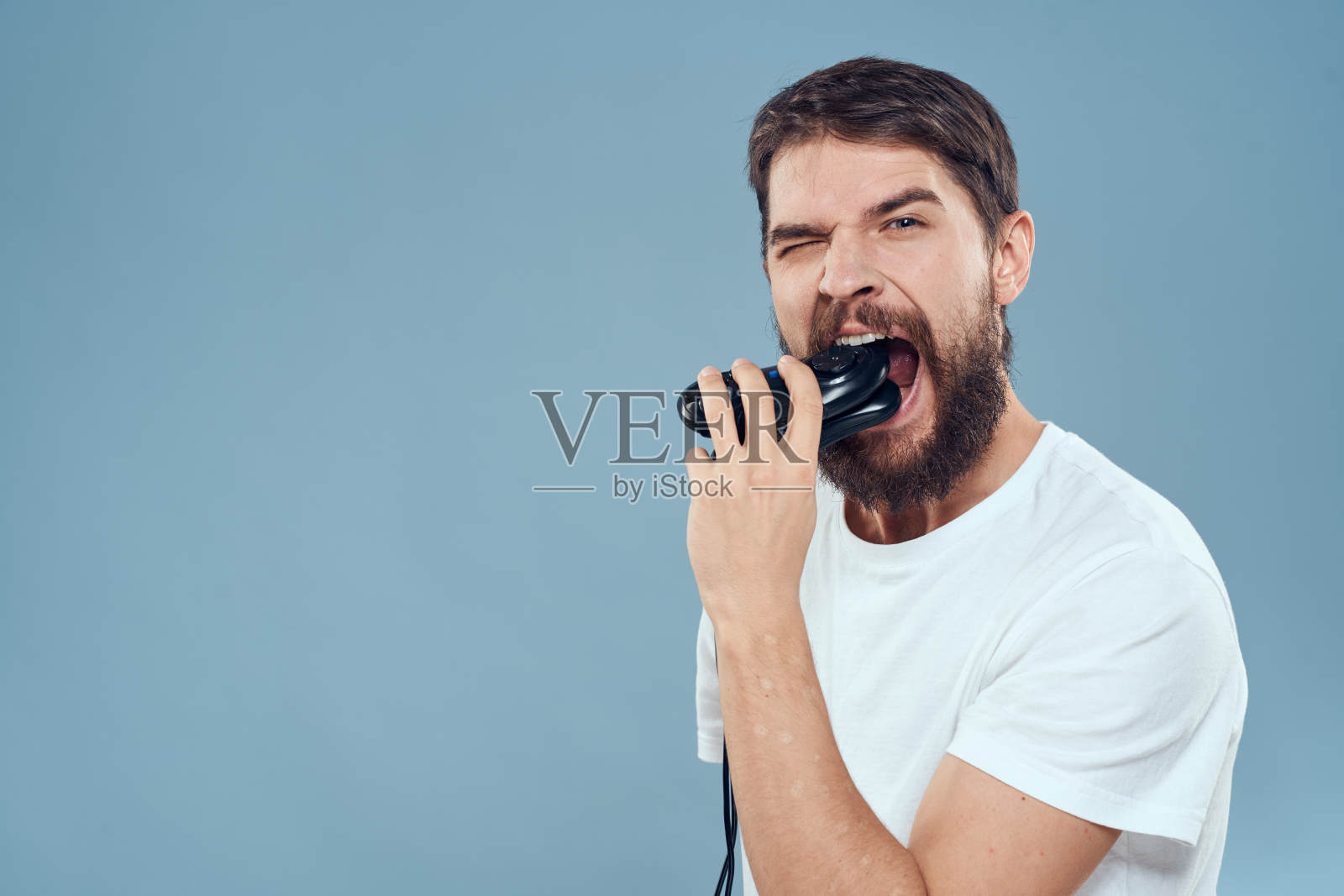 一个穿着白色t恤，手里拿着操纵杆的男人玩着游戏机娱乐情绪照片摄影图片