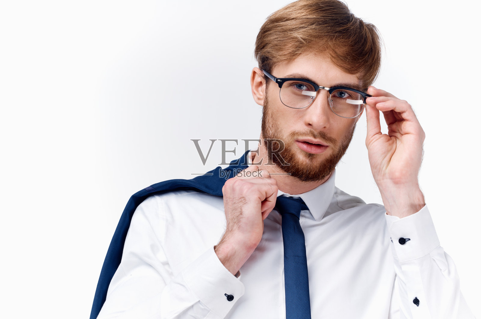 一个英俊的金发男子的肖像，穿着经典的西装，脸上戴着眼镜，肩上披着一件夹克照片摄影图片