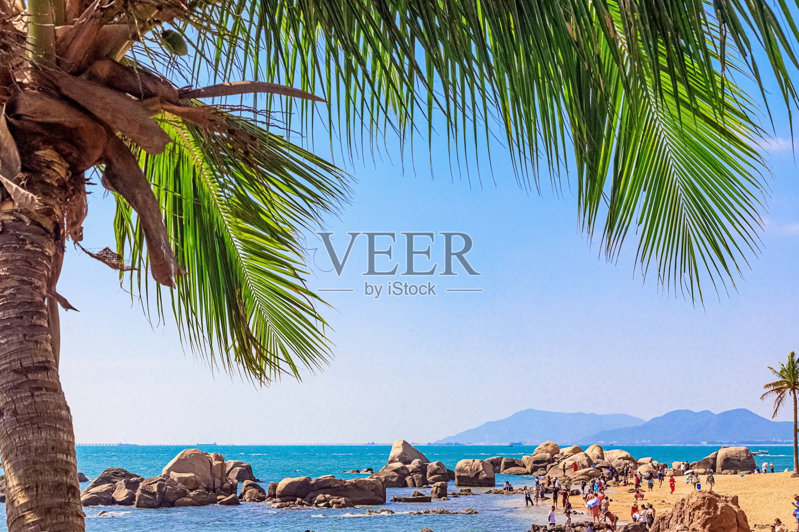 南海海岸的景色，沙滩，大岩石和绿色棕榈树。三亚,中国。照片摄影图片