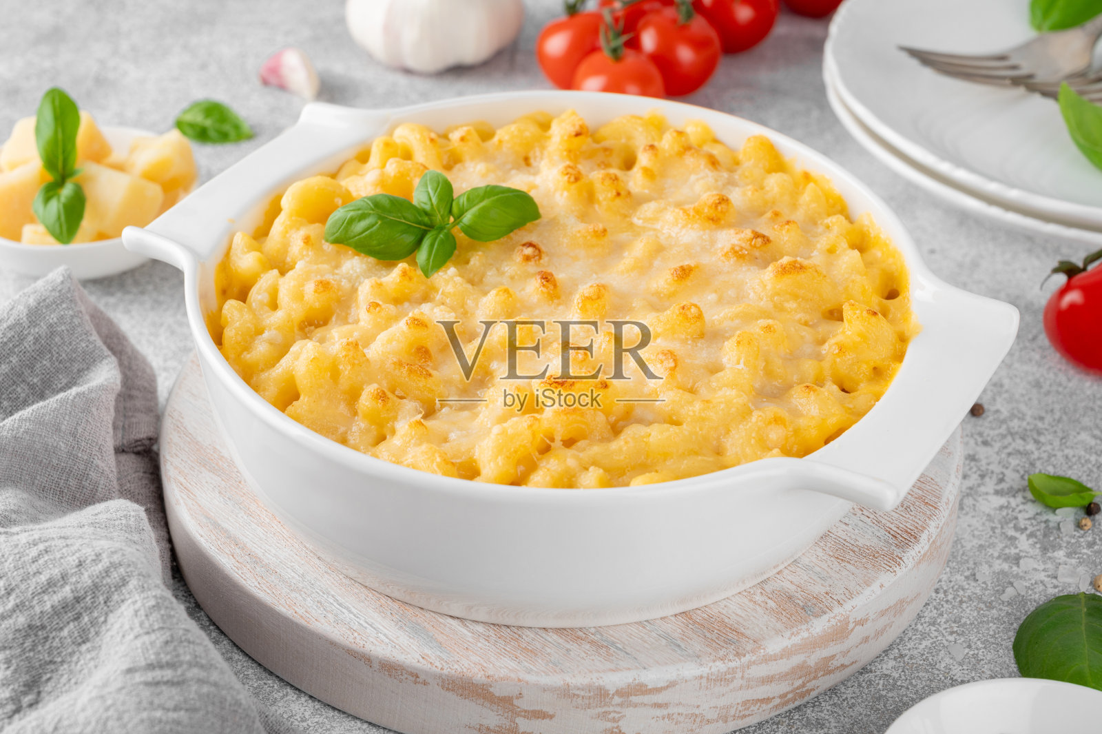 灰色混凝土背景上，木板上的白色烤盘里装着通心粉和奶酪。美国菜，安慰食物。副本的空间。照片摄影图片