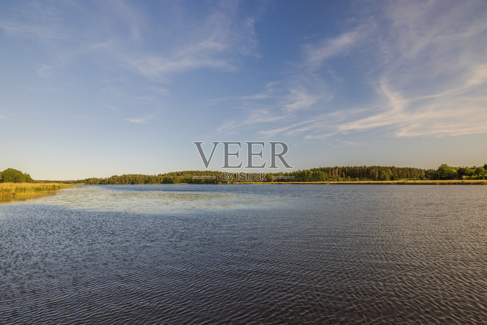 宁静蔚蓝的湖面美景与地平线上无边无际的蓝天天衣无缝地融为一体。瑞典。照片摄影图片