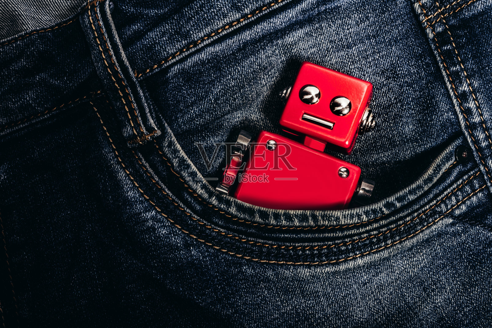 裤子口袋里的红色机器人玩具照片。照片摄影图片