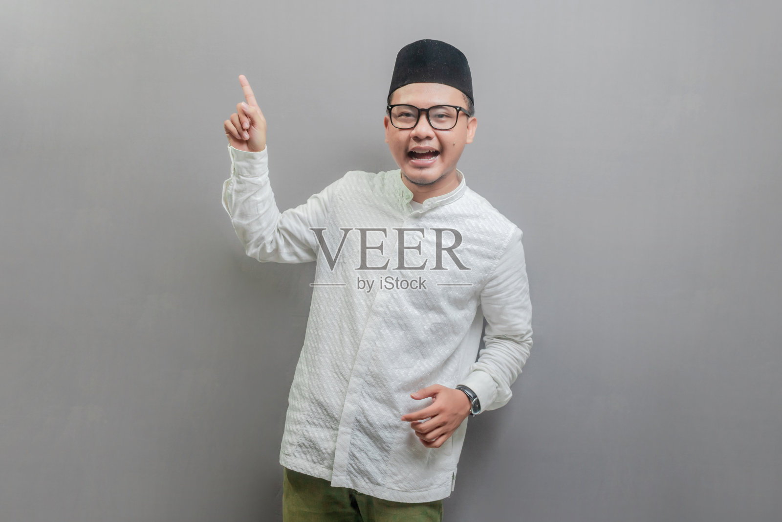 一名亚洲穆斯林男子站在镜头前，用手指着空地照片摄影图片