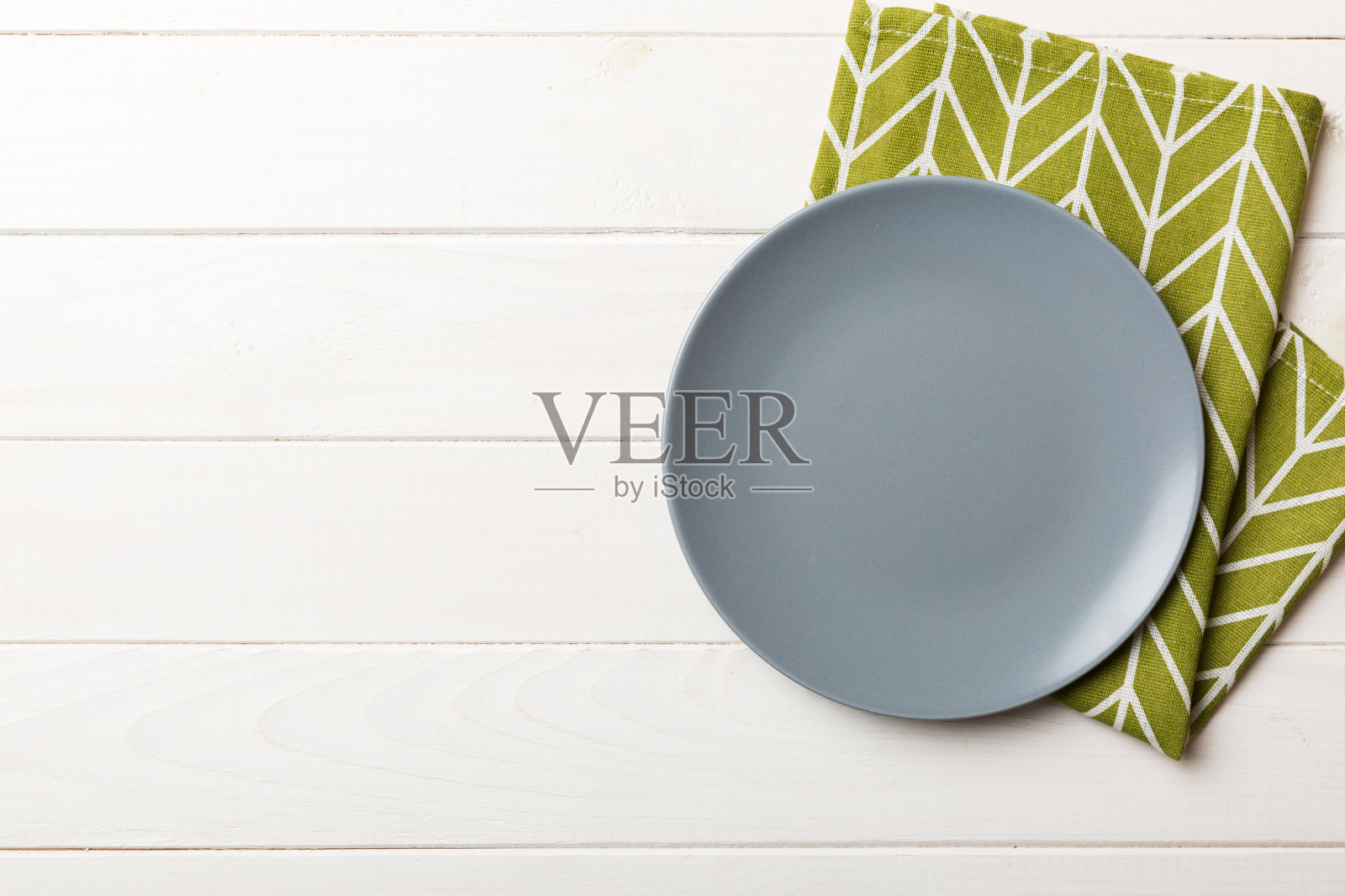 彩色背景上的俯视图，桌布上的空圆形灰色盘子用于食物。空盘子放在餐巾上，为你的设计留出空间照片摄影图片