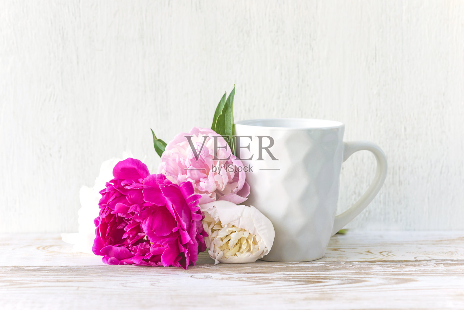 白色的咖啡杯和一束粉红色，紫色的牡丹花在白色的油漆木制背景照片摄影图片