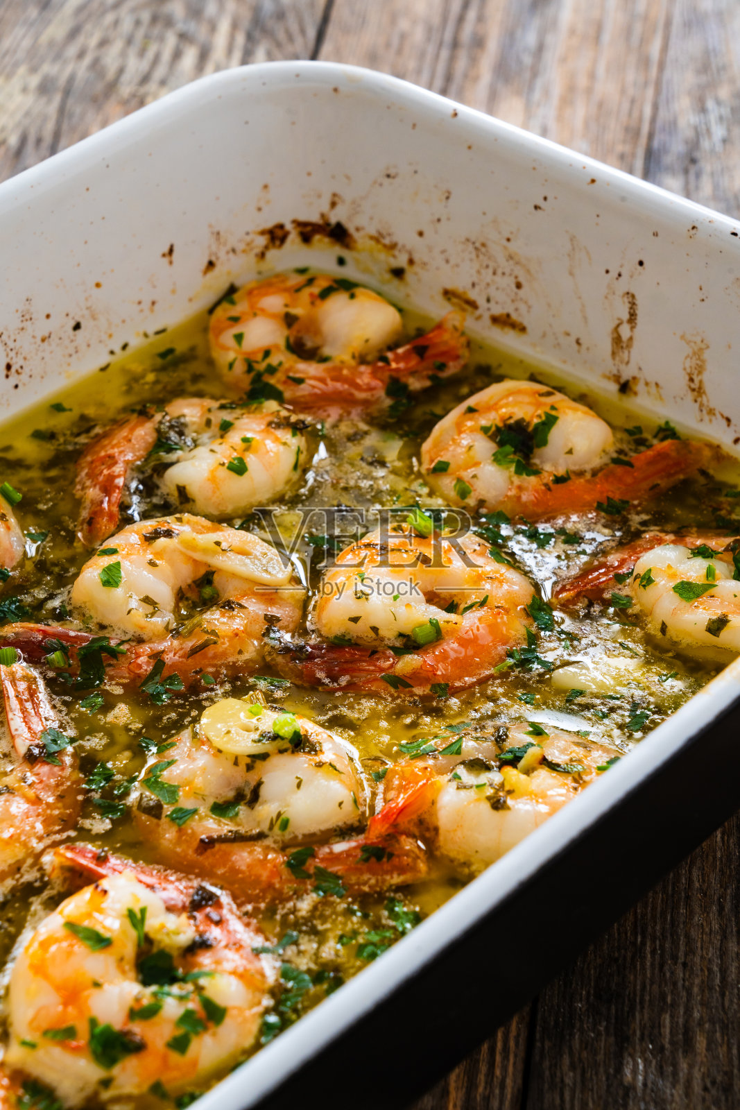 在木桌上的煎锅中加入橄榄油和香芹蒜炒虾照片摄影图片