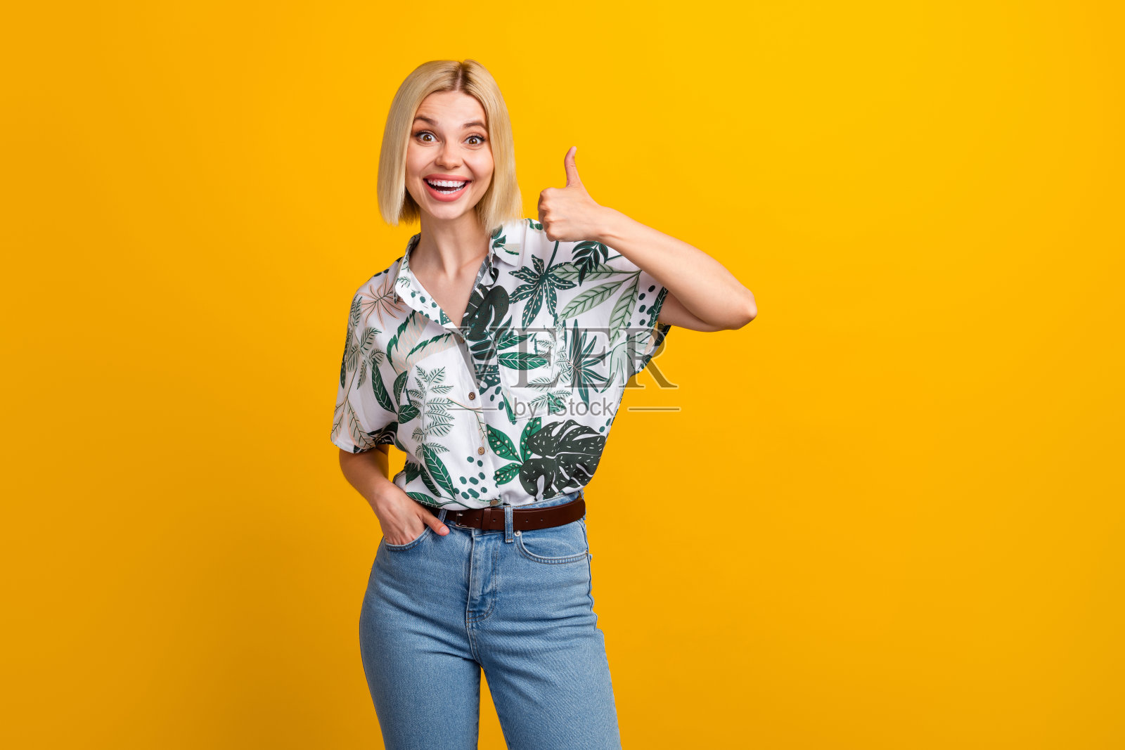 可爱的年轻女士的照片肖像拿着相机亲吻嘴唇自拍穿着时髦的树叶印花服装孤立的黄色背景照片摄影图片