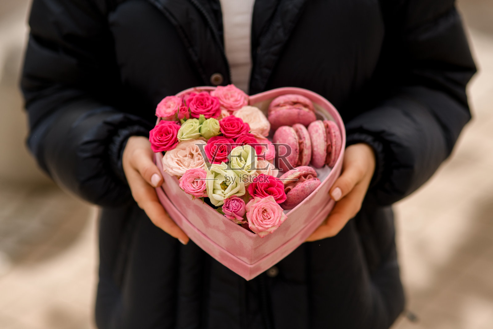 手里捧着一束鲜花和心形的马卡龙照片摄影图片
