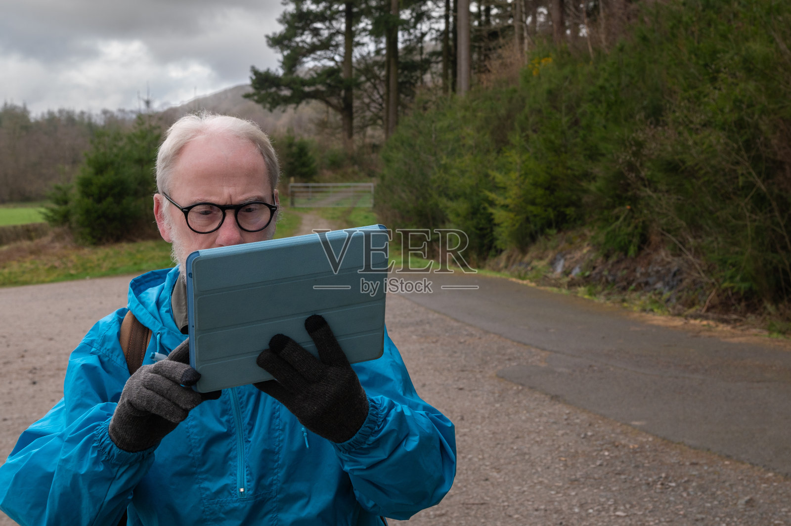 退休的男人看着他的数码平板电脑照片摄影图片