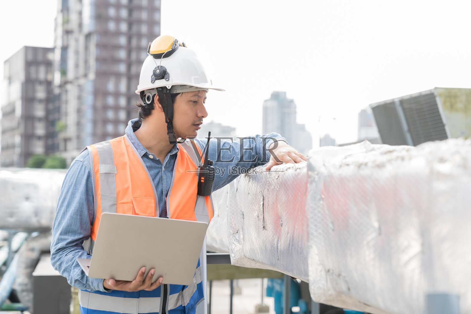 男工程师或男技术人员使用笔记本电脑维护管道冷却AHU通风，空调。亚洲男工程师维修暖通空调系统管道照片摄影图片